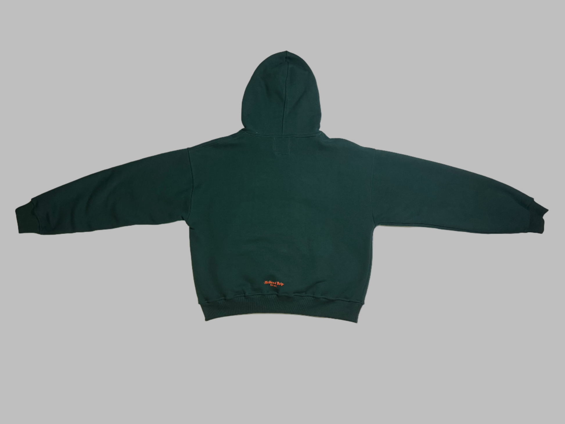 Green hoodie on a white mattress with a brown teddy bear in the background